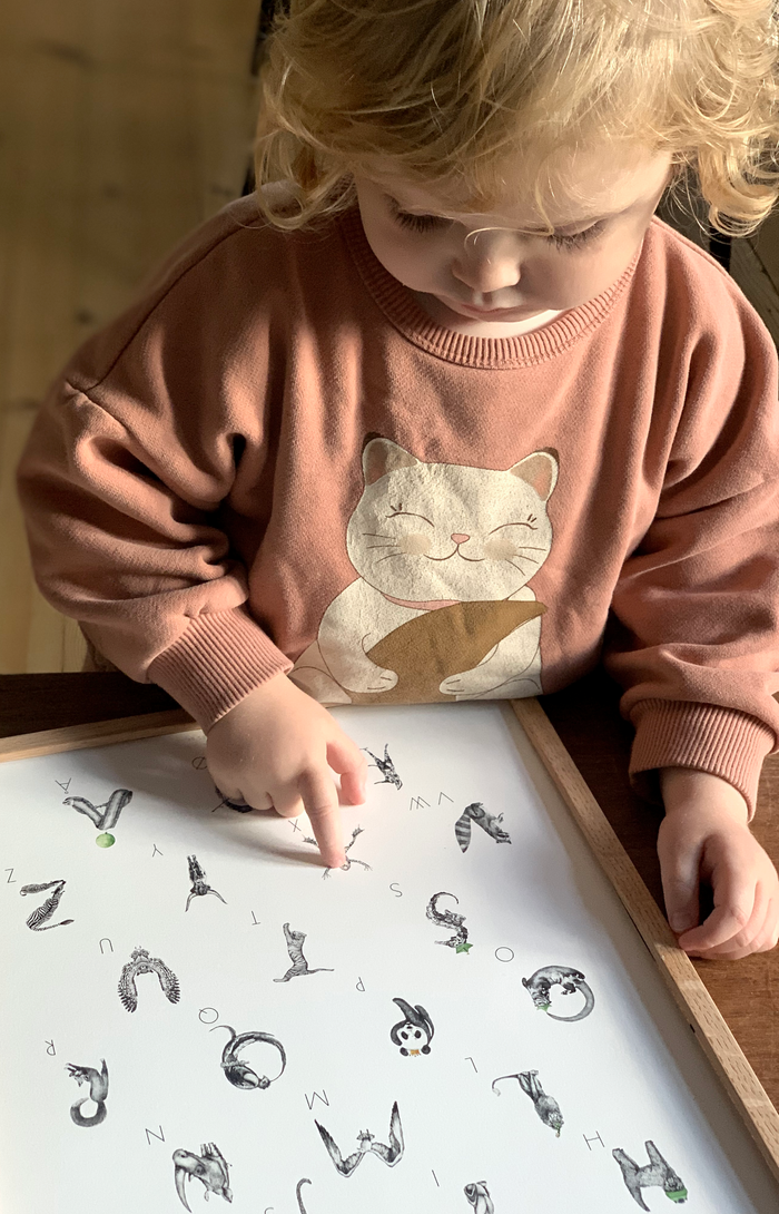 Pige peger på håndtegnet alfabet plakat med dyr